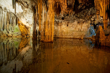 Imposing stalactites and stalacmites reflecting in a small underground lake inside the limestone cave (Tropfsteinhöhle) Grotta di Nettuno in Sardegna (Italy) © Adrian