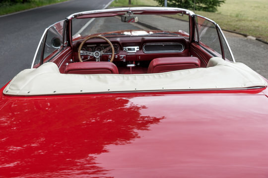 Red old cabriolet is parked at the roadside
