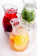 Cold and refreshing citrus cocktail with grapefruit and orange, strawberry, apple, lemon and herbs. Water for detox or dieting in glass jug on white background, copy space. Homemade drink.