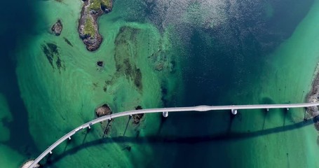 Aerial top-down pan shot of beautiful road bridge in amazing fjord scenery with green and blue water shades. - Powered by Adobe