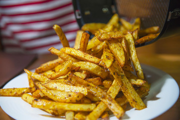 Delicious French fried potato mix with chilly powder on wooden table - traditional fast food concept