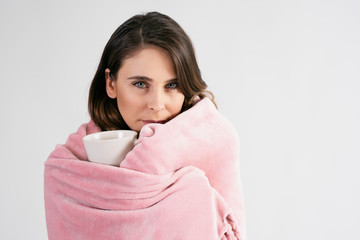 Woman wrapped in blanket holding a mug of hot tea