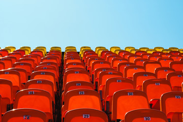 Fototapeta premium red plastic seats against a bright blue sky