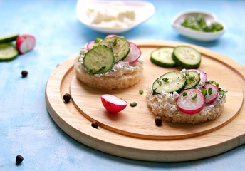 White bread sandwiches with salted cottage cheese, fresh radish and cucumber on a light blue background. Healthy food.