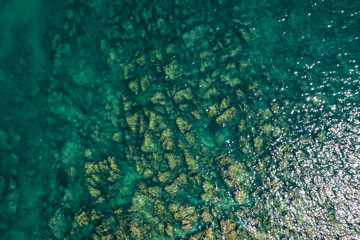 Fototapeta premium Aerial view of rocky seaside. Rocky stones in the ocean. Aerial photography of beautiful rocky seashore.