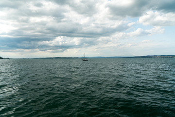 Naklejka premium sailboat returns to the harbor at Altnau on Lake Constance with a storm slowly moving in