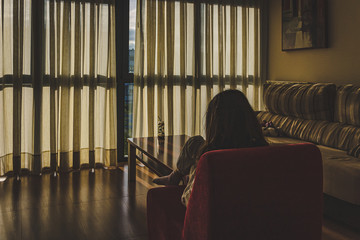 girl alone in front of a dimly lit window