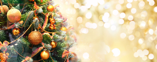 Christmas tree decorated with Golden balls toys on a blurred, sparkling and fabulous fairy background with beautiful bokeh, copy space.