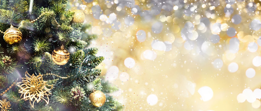 Christmas tree decorated with Golden balls toys on a blurred, gold sparkling and fabulous fairy background with beautiful bokeh, copy space.