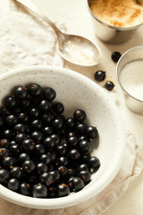 Ripe and tasty freshly harvested organic black currant with water drops and sugar in white ceramic bowl close-up top view.Homemade preserved fruit or berries preparation.Healthy vegan snack