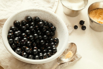 Ripe and tasty freshly harvested organic black currant with water drops and sugar in white ceramic bowl close-up top view.Homemade preserved fruit or berries preparation.Healthy vegan snack