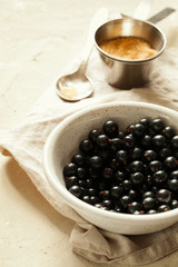 Fototapeta na wymiar Ripe and tasty freshly harvested organic black currant with water drops and sugar in white ceramic bowl close-up.Homemade preserved berries preparation.Healthy vegan snack.Vertical orientation