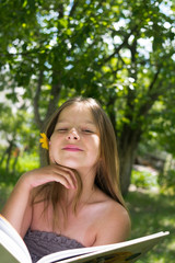 Beautiful girl reading a book and lying on a hammock in the garden