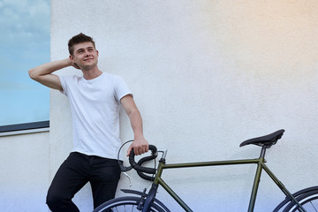 Handsome hipster man posing with bicycle in the city.