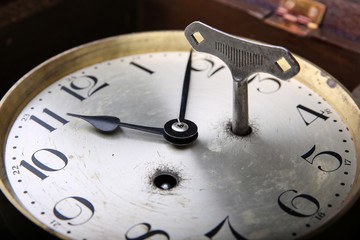 dial of analog clock with Arabic numerals and a clockwork key.