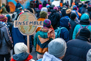 Environmental activists march in city. A French sign is seen close up, depicting planet earth and...