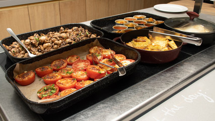 Selection of self service catering continental breakfast buffet display, catering brunch table food buffet filled with delicious food, grill, bacon, eggs, hot station in a hotel or restaurant setting