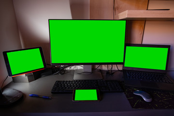 Computer monitor, laptop, tablet and smartphone screens on top of a desktop
