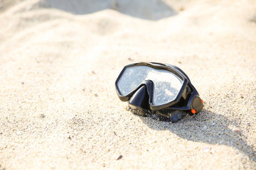 black diving mask on the yellow sand close up with copy space