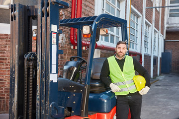 Forklift driver with forklift in front of the warehouse