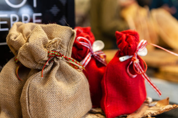 Seasonal products sold at Xmas market. Small hessian gift sacks are seen close up, for sale on a stall during a local Christmas fair, cute wrapping with small red bows for gifting.