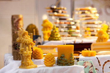 Seasonal products sold at Xmas market. A close up view of hand sculpted wax candles on a stall during a local seasonal craft fair, festive decorations for sale with copy space above.