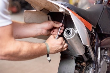 Fototapeta premium Motorbike mechanic repairing an exhaust pipe system at garage .