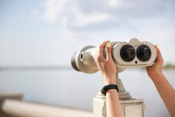 woman's hands holding observation binocular against skyline close up with copy space