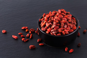 Super brain food dry Goji berry in black ceramic cup on slate stone board with copy space