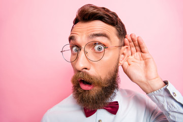 Close up portrait of funny funky loony geek astonished hipster holding palm near ear isolated pastel background