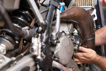 Fototapeta na wymiar Motorbike mechanic repairing an exhaust pipe system at garage .