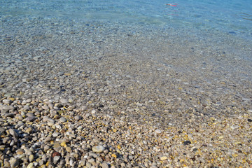 Sea stones in the sea water. Pebbles under water. The view from the top. Nautical background. Clean sea water. Transparent sea.