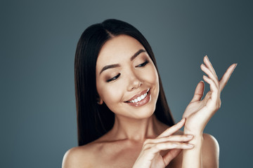 Fresh and clean. Beautiful young Asian woman smiling while standing against grey background