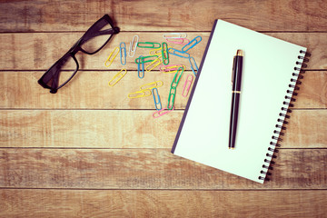 Pen, book, paper plugs and glasses for working on wooden table