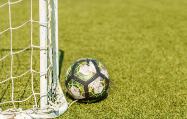 the net from the football goal and the ball in focus the football field is blurred in the background