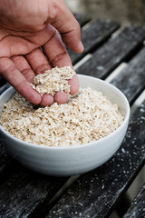 man taking some rolled oats from a bowl