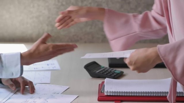 Tracking left of female and male hands doing handshake. Then man asking woman to take seat by hand gesture and woman giving document to man