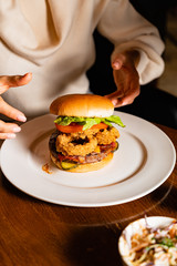 .Young woman eating burger in restaurant