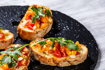 Bruschettas on black stone plate on wooden background