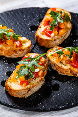 Bruschettas on black stone plate on wooden background