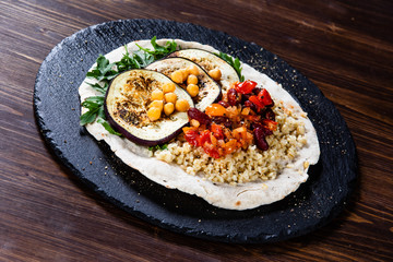Groats with sauce and vegetables on tortilla