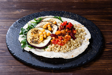 Groats with sauce and vegetables on tortilla