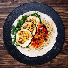 Groats with sauce and vegetables on tortilla