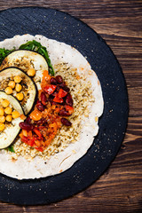 Groats with sauce and vegetables on tortilla