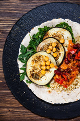 Groats with sauce and vegetables on tortilla