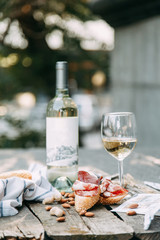 Fototapeta na wymiar Bruschettes and a picnic with prosciutto. White wine with a glass in nature in Italy.