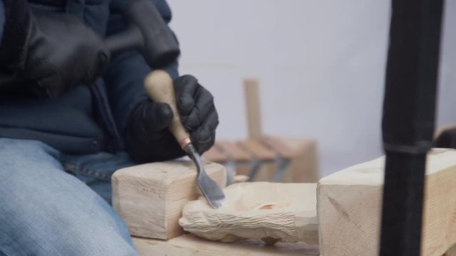 Close up of hands of craftsman carve with a gouge in the hands on the workbench in carpentry