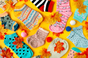 Socks for autumn on a yellow background. Colorful socks and maple leaves on a yellow background....