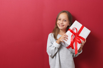 cute cheerful girl in a Christmas hat on a colored background holding a gift