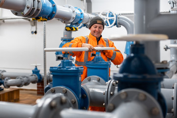 Diligent worker in public water utility turning a valve to open a pipe
